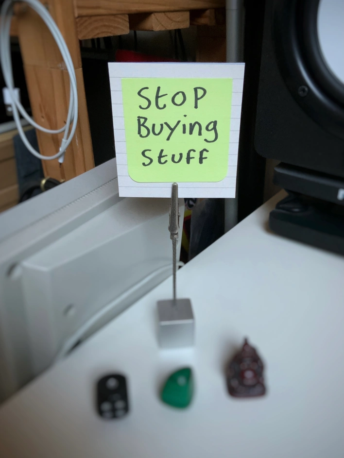 A note on a desk with the words "Stop Buying Stuff"